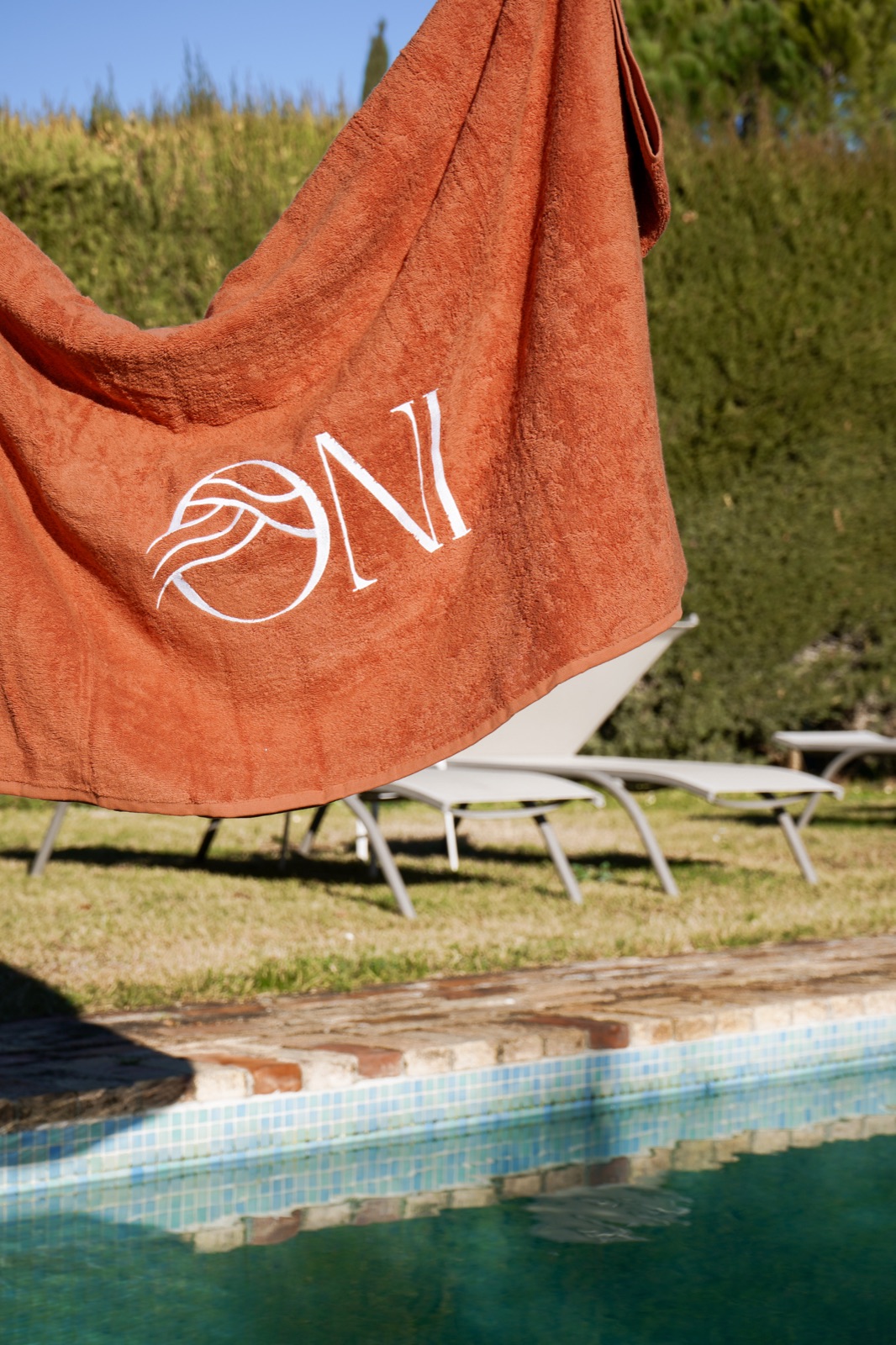Serviette de bain orange personnalisée par broderie près d’une piscine