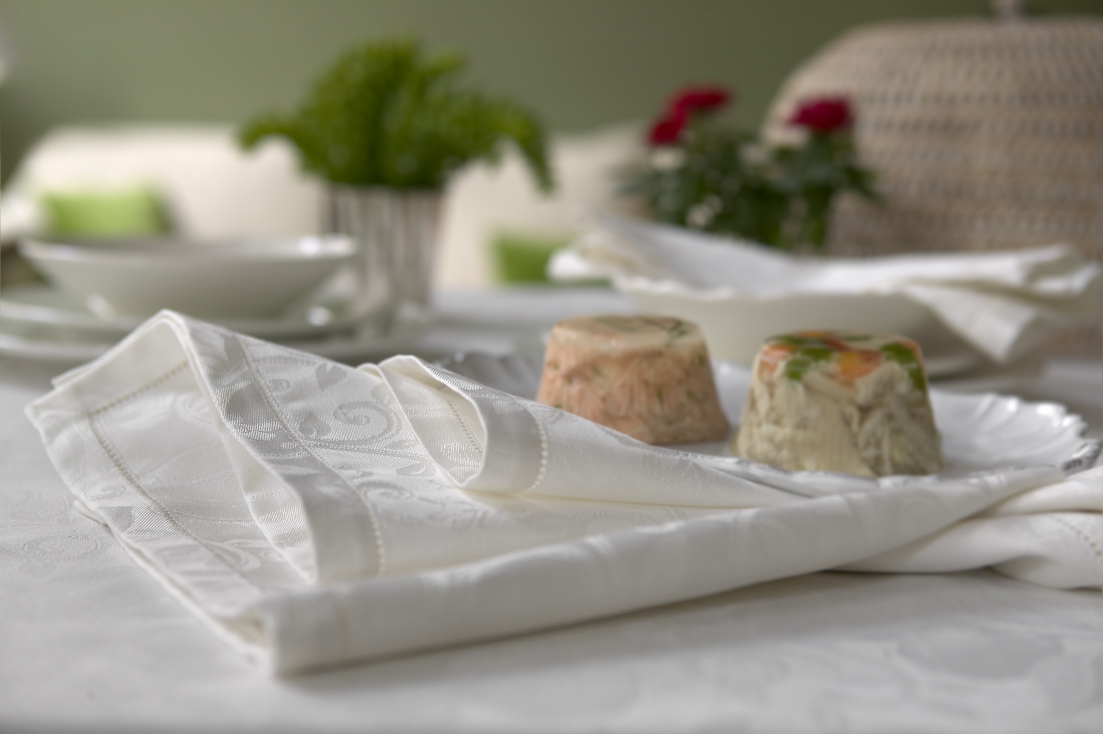 Détail d’une table dressée avec du linge blanc en jacquard
